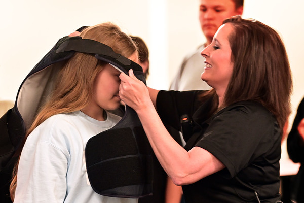 Northeast Mississippi Community College Assistant Chief of Campus Police Melissa Pearson helps a participant in the college's Career Development Academy summer camp try on a bullet-resistant Kevlar vest worn by campus police officers during a hands-on public safety demonstration on the Booneville campus. Campers learned about the purpose of the protective equipment while also receiving instruction on digital safety, cyber awareness, online scams and responsible decision-making both online and in everyday situations.  