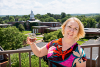 Susan Perkins poses with a glass of rum on the balcony of Raymond Hall, overlooking the Academic Quad.