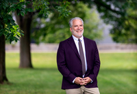 Andrew Mast poses for a photo in front of The Crane School of Music.