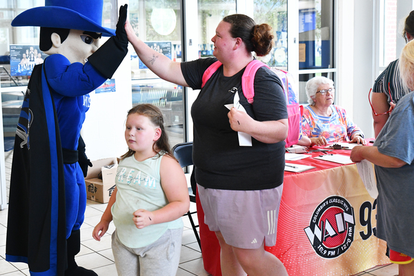 Lindsey Wilson University athletics mascot Blue Raider Bob welcomes Catherine Loy and daughter, Josie, 6, both of Columbia, to the WAIN Splash Bash on Saturday, Aug. 1, held at the university’s Doris and Bob Holloway Health & Wellness Center.