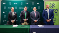 Four men in suits smile behind a table at the SRTC and Thomas University articulation agreement signing, with signed documents and pens nearby.