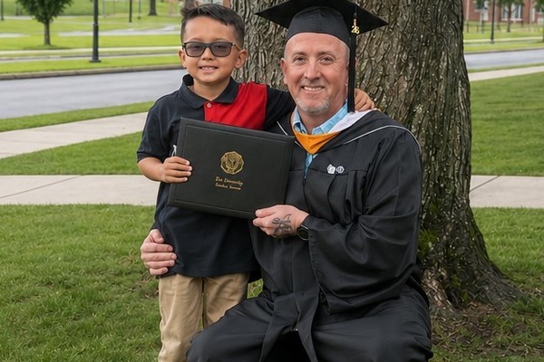 Michael White is pictured with his son after receiving his Bachelor of Science in Emergency Management during Lee University's summer commencement ceremony as the first graduate of the university's online Emergency Management program.