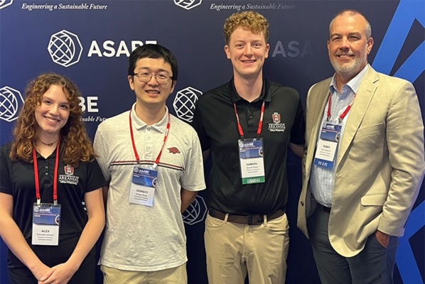 Students pose for picture in front of ASABE banner