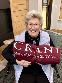 Marilyn Horner holds a blanket with the Crane School of Music logo on it.