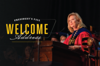 Stan State President Britt Rios Ellis in academic regalia speaking at a lectern.