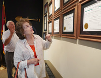 Kathy points toward framed legislative documents as Larry looks at the display inside the William “Billy” McCoy Mississippi Heritage Room.