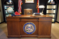 A legislative desk displays the Mississippi state seal, flags, books, a globe, a lamp and one of Billy McCoy’s wooden walking sticks.