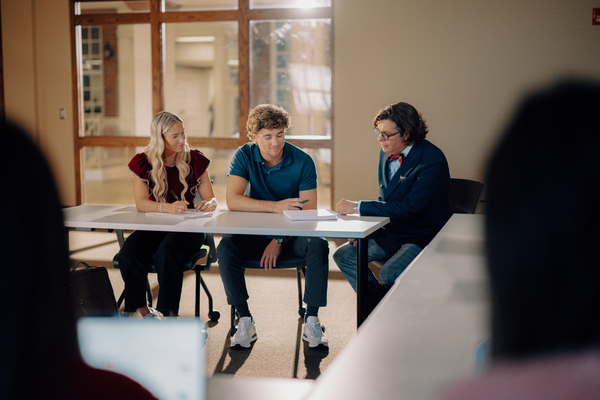 Troy University students sitting around a table learning from leadership. 