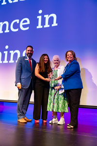Dr. Michael J. Heindl, Lisa Strong, Sandy Grisham, and Dr. Ginger Robbins on stage as Strong accepts the award from the Northwest administration.