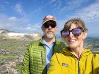 Michael Rygel and Page Quinton take a selfie with a glacier and mountains in the background.