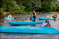 Students laugh while kayaking in the river.