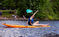 A student gets ready to paddle on a standup paddleboard.