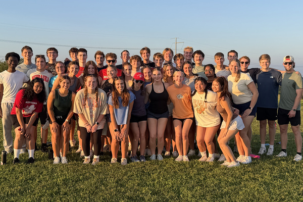 About 40 young men and women in casual attire pose for an outdoor photo.
