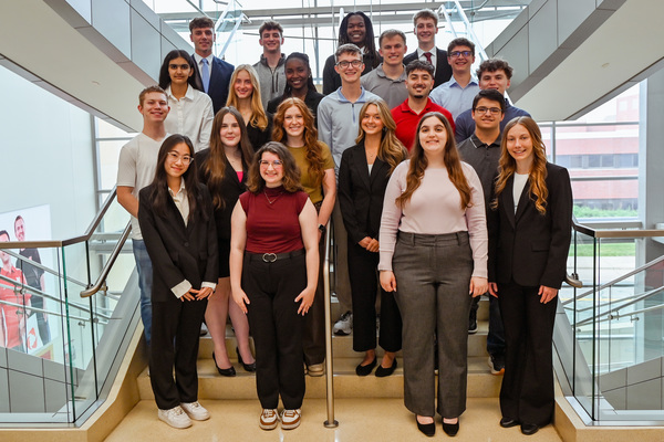 Twenty-one University of Nebraska–Lincoln students pose for a photo on a staircase in Howard L. Hawks Hall.