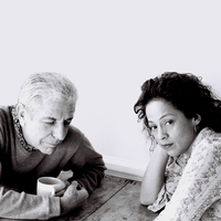 Leonard Cohen and Perla Batalla have their photo taken sitting at a table with coffee.