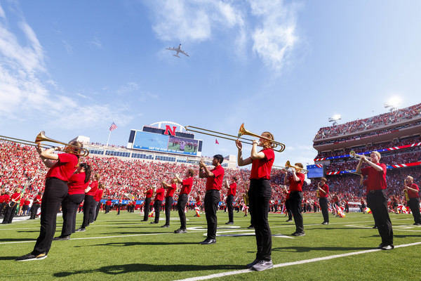 Members of the Cornhusker Marching Band — wearing red polo shirts, black pants and black shoes — perform during a day game at Memorial Stadium.