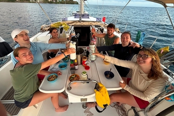students cheers their beverages on a boat in the ocean.