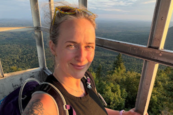 New York State licensed outdoor guide Jess Heck takes in the view from the fire tower atop Azure Mountain in the Adirondacks. Heck will lead SUNY Potsdam’s new beginner-friendly hiking course through PLACE this fall. (Photo courtesy of Jess Heck)
