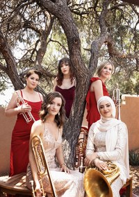 Seraph Brass pose with their instruments near a tree, wearing formal gowns.