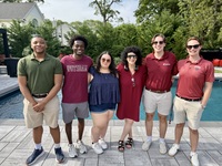 Phyllis Farrantello stands with SUNY Potsdam students near her pool during an event at her home.