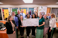 SUNY Delhi staff, students, and SFCU leadership hold a large check in front of SUNY Delhi's Bronco Basics food pantry.