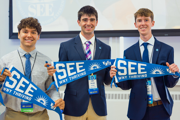 Students hold a pennat that says SEE.