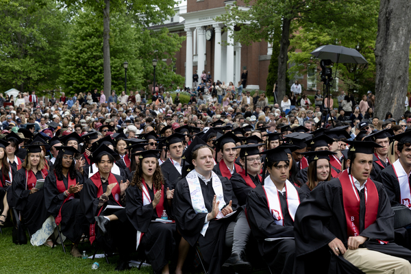 Bates College graduates in caps and gowns seated on the Historic Quad during Commencement.
