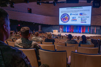 Military personnel and family members viewing briefing slides on support programs. 