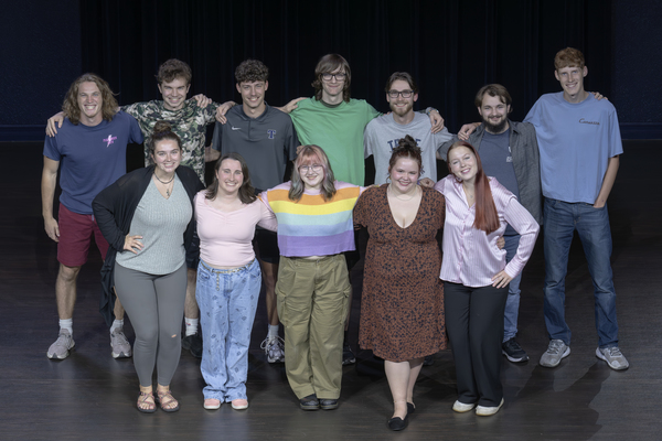 Cast in two rows on theatre stage