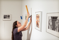 A student installs artwork for a show in the Gibson Gallery at SUNY Potsdam.
