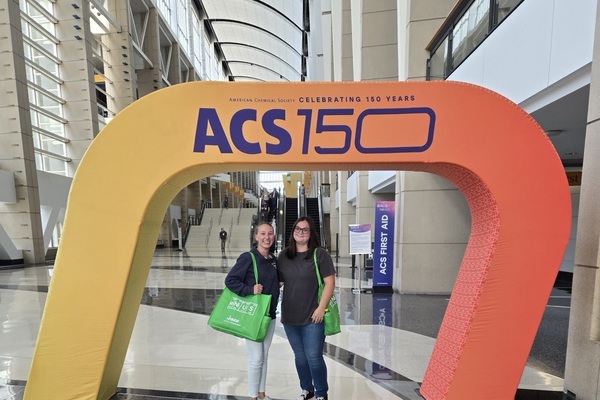 Two female students under ACS 150 arch