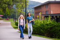 Two students walking and smiling on the SUNY Delhi campus.