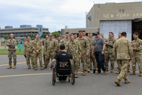 Man in wheelchair is greeted by Soldiers.