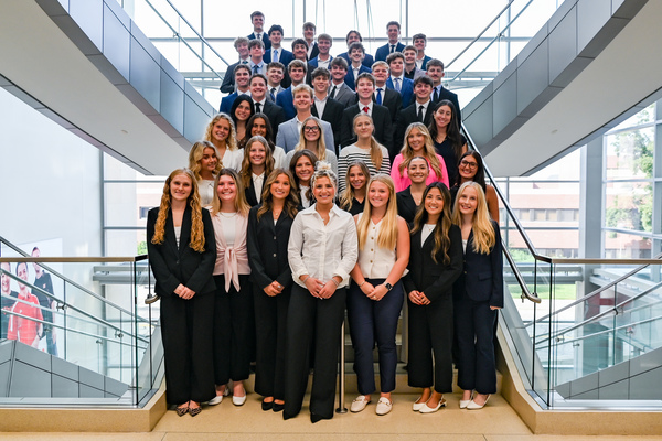 About 45 Husker students in business attire pose on a staircase in Howard L. Hawks Hall.