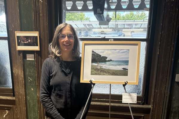 SUNY Potsdam Associate Professor of Art Iggy Beerbower poses next to her featured photograph, “Into the Waves,” at a show during the London Design Festival. 