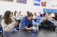 Page Quinton looks through a microscope and laughs while talking to students.