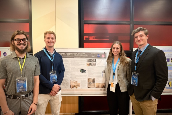 Four students posing with their research poster.