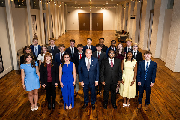 Group of students standing with university president in the front center.