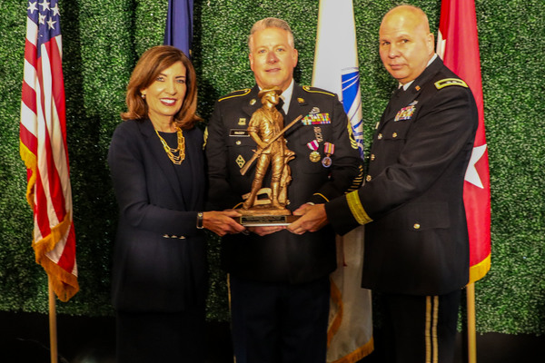 New York Governor Kathy Hochul and Major General Ray Shields, the adjutant general of New York, present a Minute Man statuette to Master Sgt. Dan McCoy, during his retirement ceremony at Normanside Country Club in Delmar, New York on October, 25, 2026. McCoy, who is the Albany County executive in civilian life, retired after 37 years of service. (U.S. Army National Guard photo by Eric Durr)