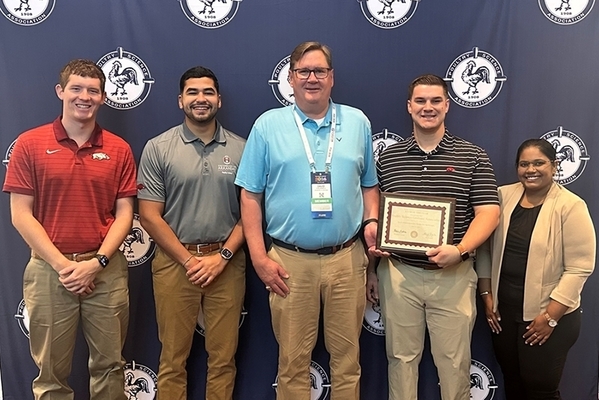 Poultry Science students stand in front of banner holding award. 