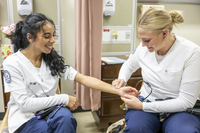 Two SUNY Canton students taking each other's pulse during a Nursing Lab class. 