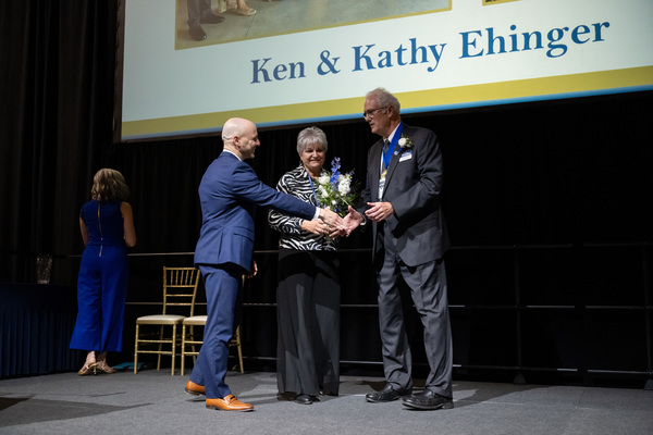 Trine University President Tony Kline, Ph.D., left, shakes hands with alumnus and trustee Ken Ehinger as he presents the university’s Pillar of Success award to Ken and his wife Kathy. (Photo by Laura Pentecost / Trine University)