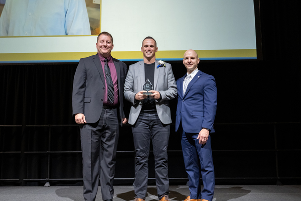 Kody Kumfer, center, a 2012 accounting and business management graduate from Trine University, receives the Distinguished Service Alumni Award from Tim Raftery, left, president of the university’s Alumni Association Board of Directors, and Tony Kline, Ph.D., university president, at the Touchstone and Homecoming Celebration Dinner on Friday, Oct. 2. (Photo by Laura Pentecost / Trine University)