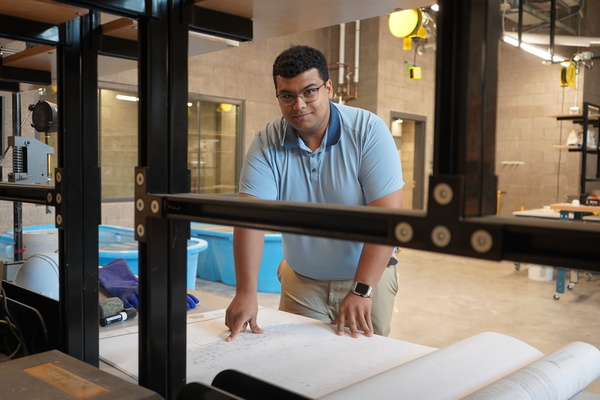 student pointing at construction plans on a table
