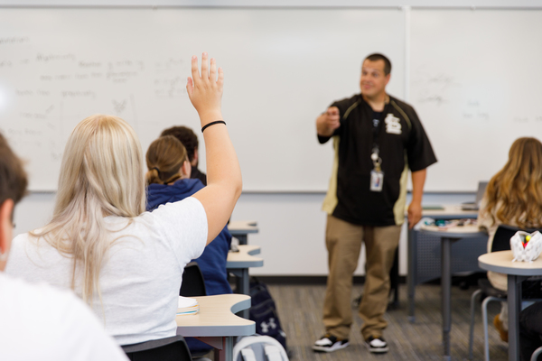 A student raises her hand to ask a question as an instructor leads a classroom discussion in a BSC dual credit course.