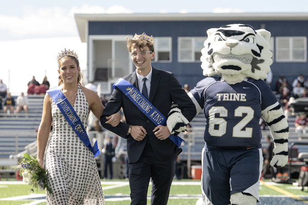 From left, Trine University's Homecoming Queen, Carly Hutcherson, and Homecoming King, Keith Knafel, are escorted onto Shive Field by university mascot Storm. (Photo by Laura Pentecost / Trine University)