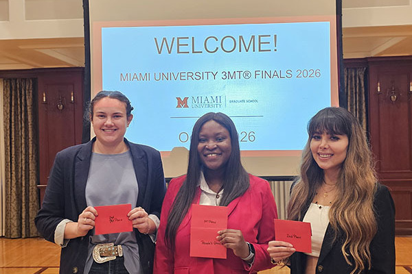 Three students are smiling, each holding a red envelope.