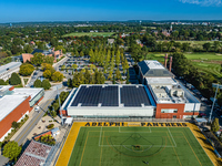Wide, drone shot of a modern campus showcasing a building with solar panels on the roof.