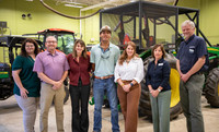 Elizabeth Harrell, Allen Corbin, Ragan Brown, Isaac Harper, Jennifer Pearce, Liz Nogowski, Dr. Jeremy Green stand in a garage in front of a tractor