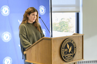 A SUNY Canton student in a green sweater speaks at a podium. 